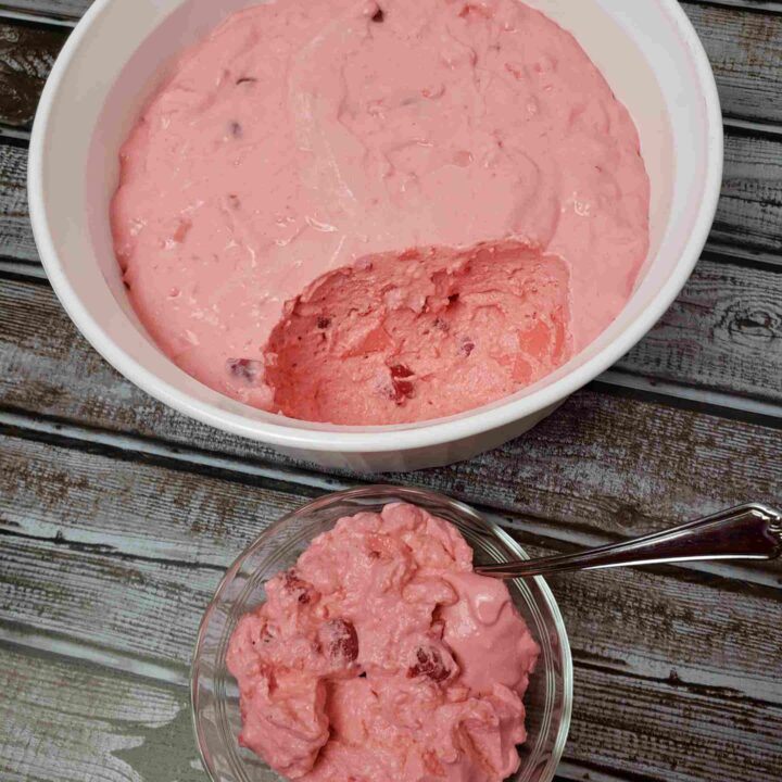 raspberry cherry jell-o in serving dish with one serving out in a small dish