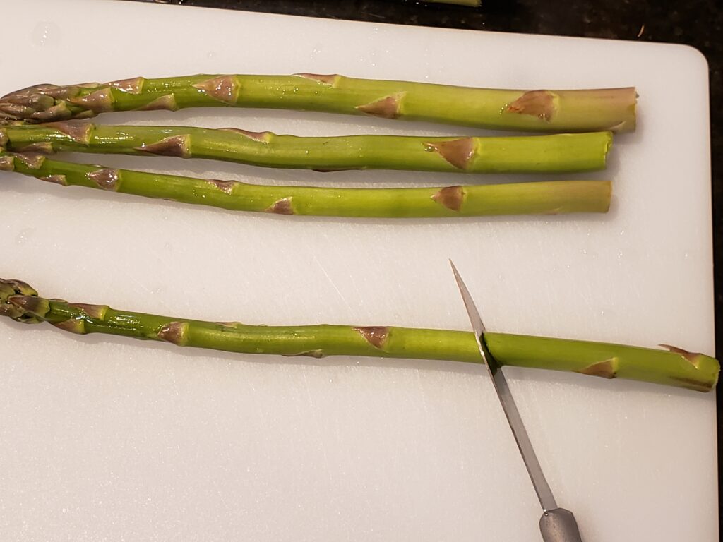 cutting asparagus spear on cutting board