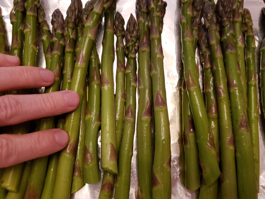 rubbing olive oil onto asparagus