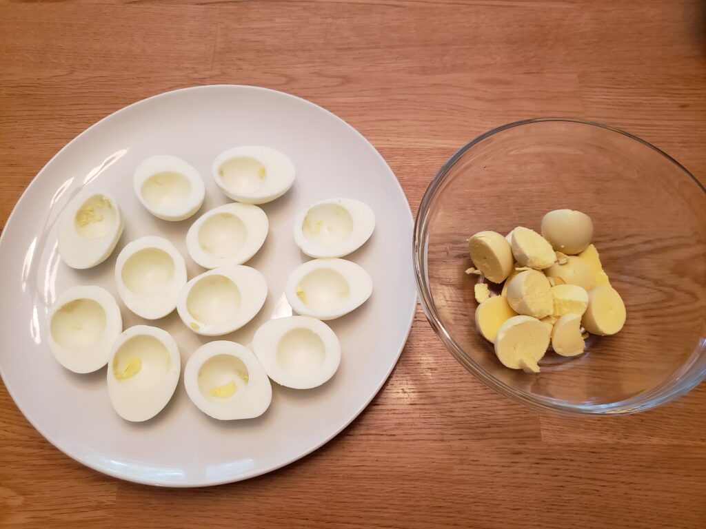 boiled eggs cut in half. whites on plate and yolks in bowl
