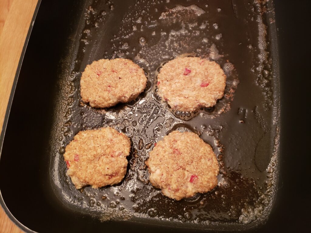 4 salmon cakes starting to cook in skillet