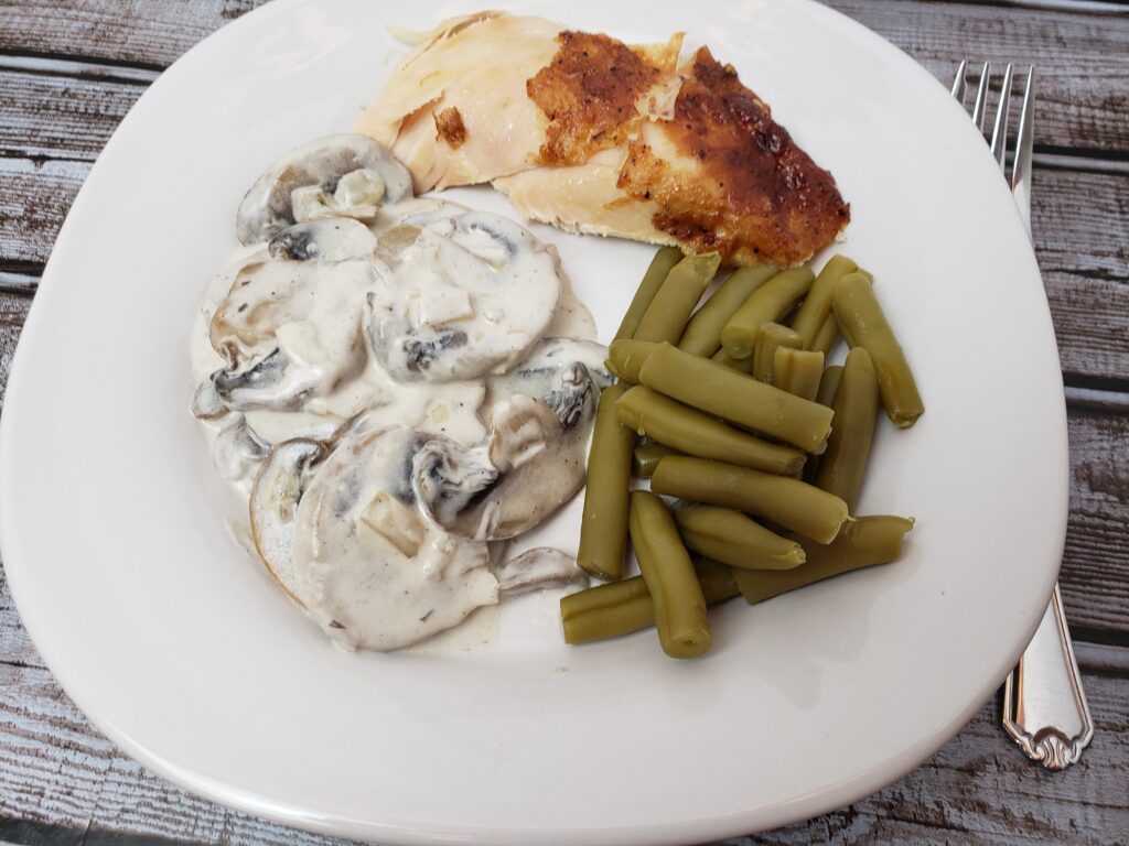 creamed mushrooms, rotisserie chicken and green beans on a white plate