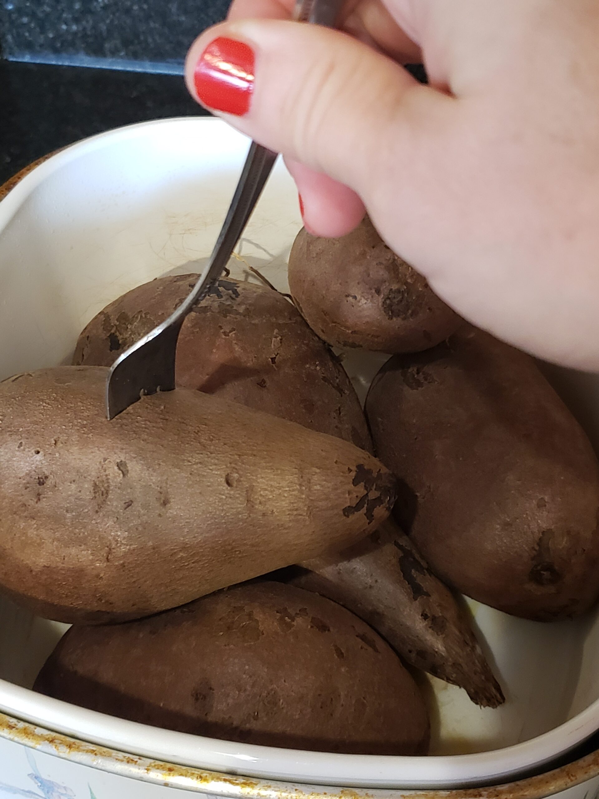 poking sweet potato with fork to test if it is done