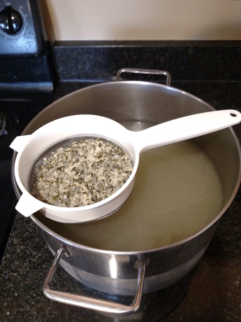 straining broth with strainer over pot