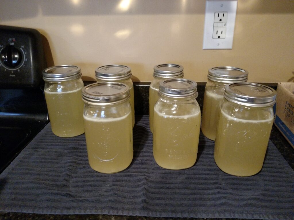 7 jars of chicken broth cooling on towel