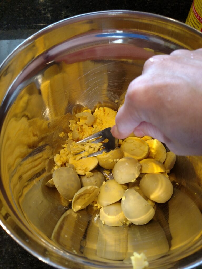 mashing egg yolks in bowl with fork