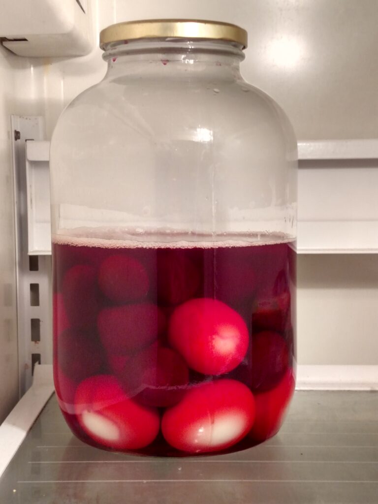 red beet eggs in jar in refrigerator
