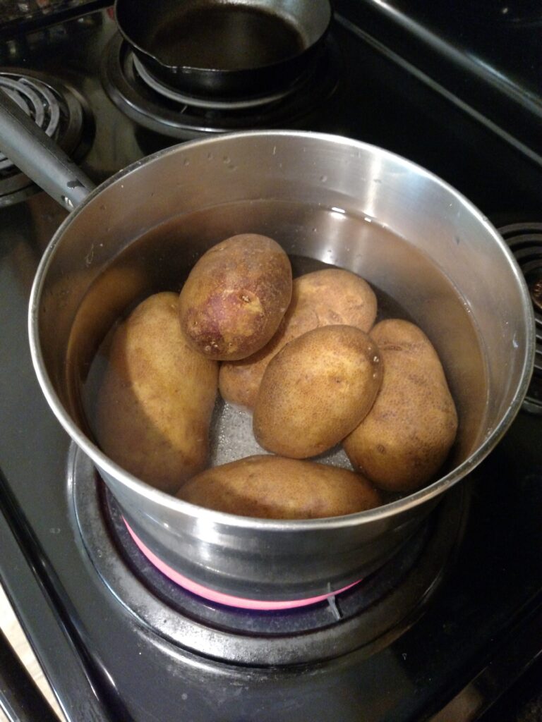 whole potatoes in water in a pan on the stove