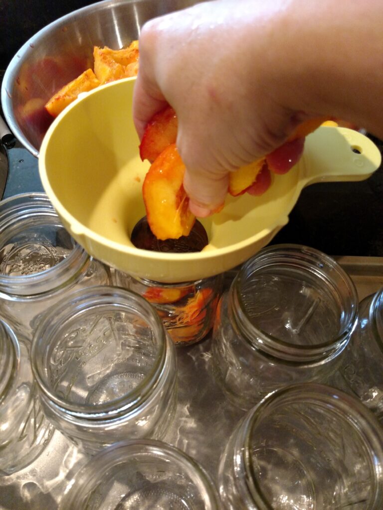 adding peaches to jars through funnel