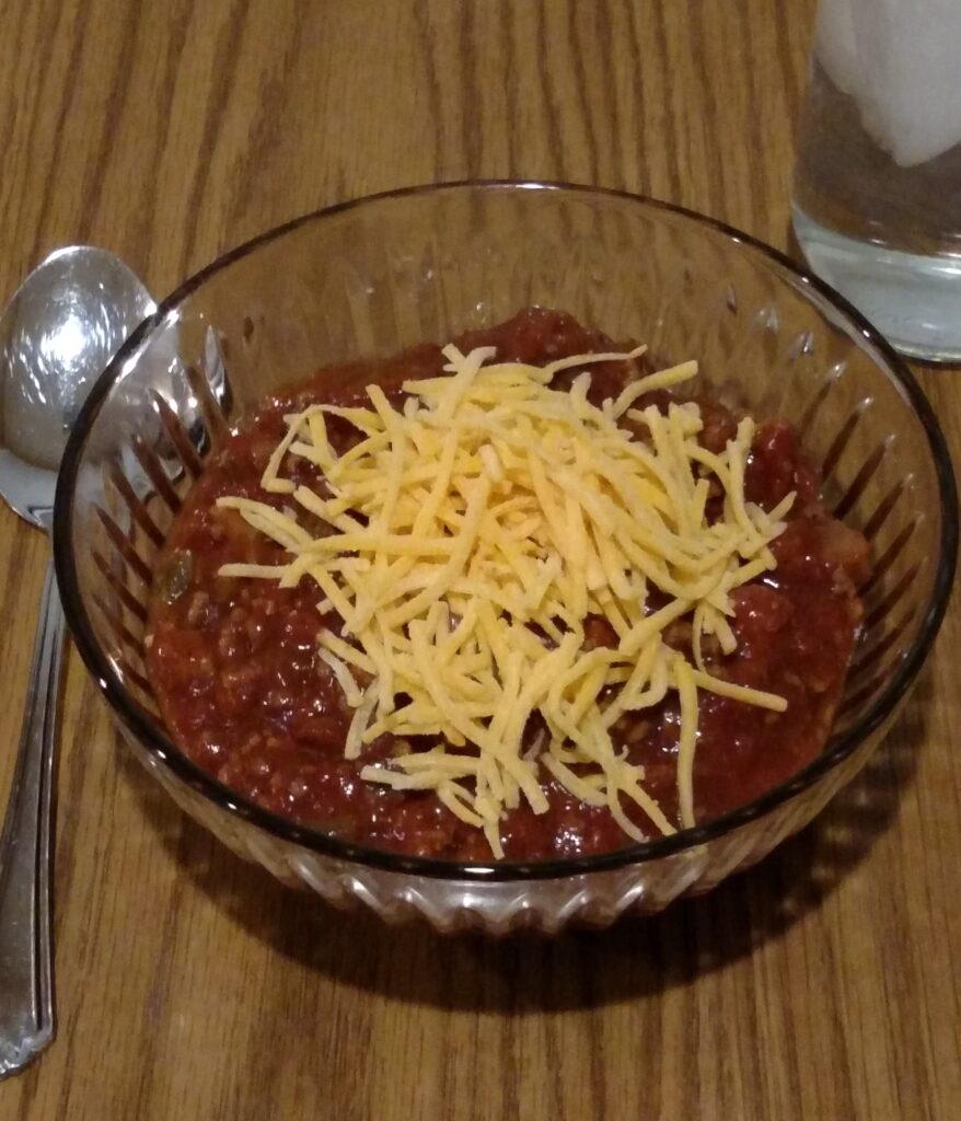 low carb slow cooker chili in serving bowl with shredded cheese on top